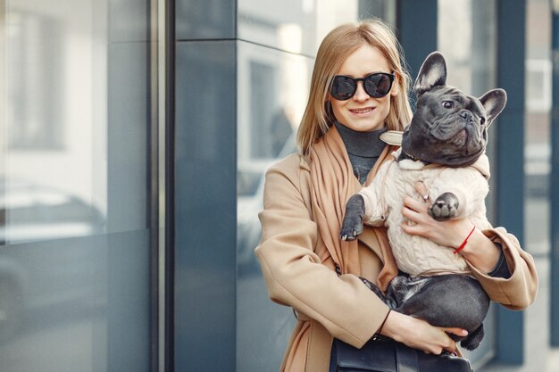 Mujer elegante con un abrigo marrón con bulldog negro