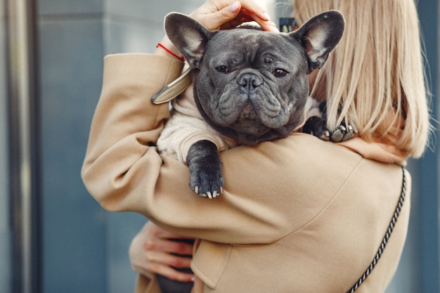 Mujer elegante con un abrigo marrón con bulldog negro