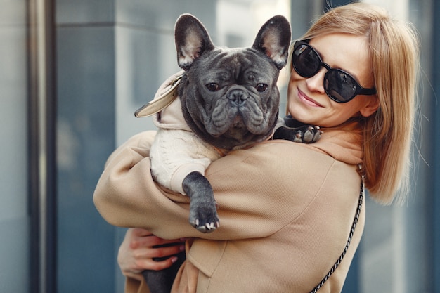 Mujer elegante con un abrigo marrón con bulldog negro