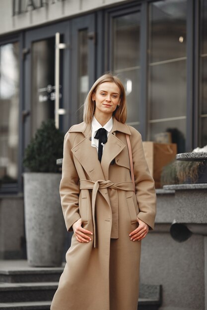 Mujer elegante con un abrigo marrón en una ciudad de primavera