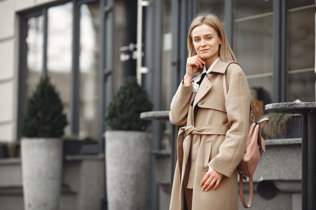 Mujer elegante con un abrigo marrón en una ciudad de primavera