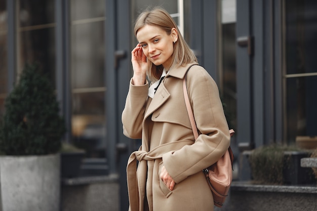 Mujer elegante con un abrigo marrón en una ciudad de primavera