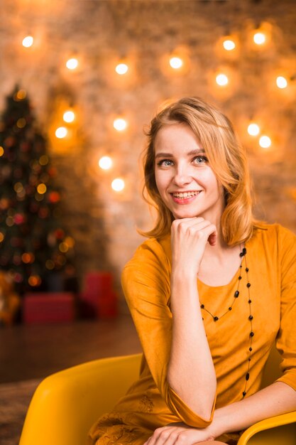 Mujer elegante y amable en habitación con luces de navidad