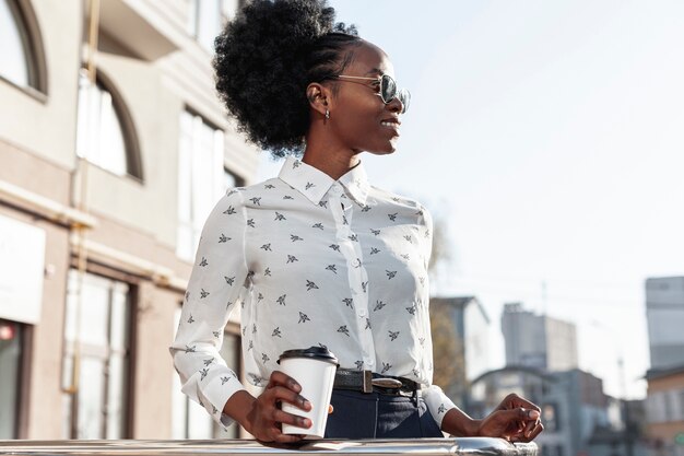 Mujer elegante de ángulo bajo con café en el balcón