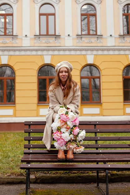 Foto gratuita mujer elegante en el banco al aire libre con ramo de flores en la primavera