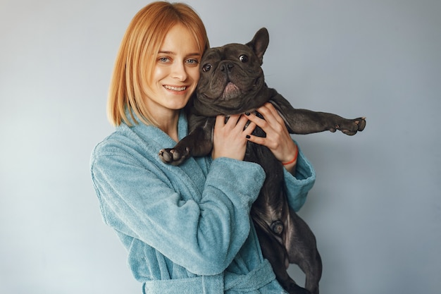 Mujer elegante en una bata de baño azul con bulldog negro