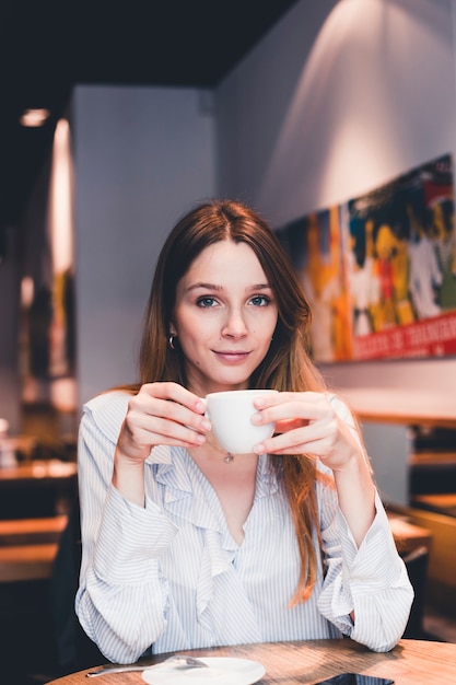 Mujer elegante bebiendo en café