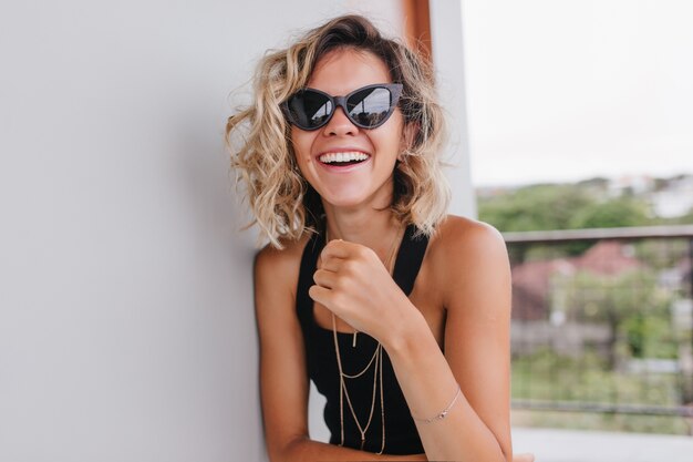 Mujer elegante con bronceado bronce riendo. maravillosa modelo femenina bromeando en la mañana.