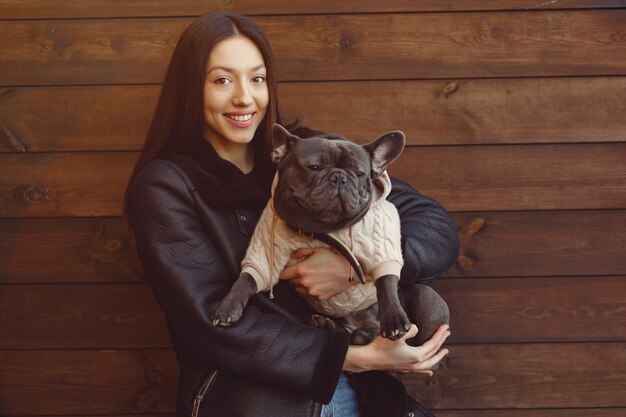 Mujer elegante en una chaqueta negra con bulldog negro