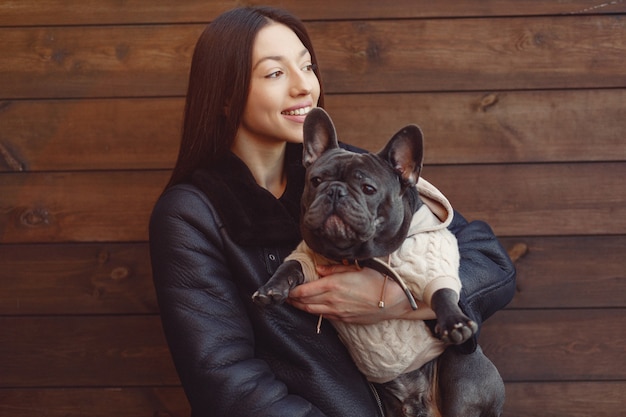 Mujer elegante en una chaqueta negra con bulldog negro