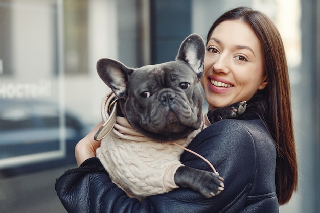 Mujer elegante en una chaqueta negra con bulldog negro