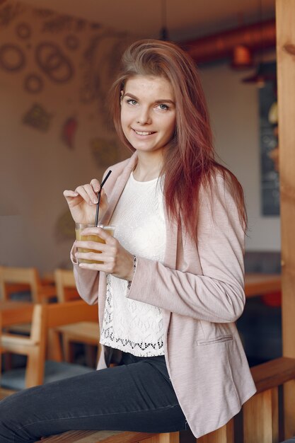 Mujer elegante en una chaqueta rosa pasar tiempo en un café