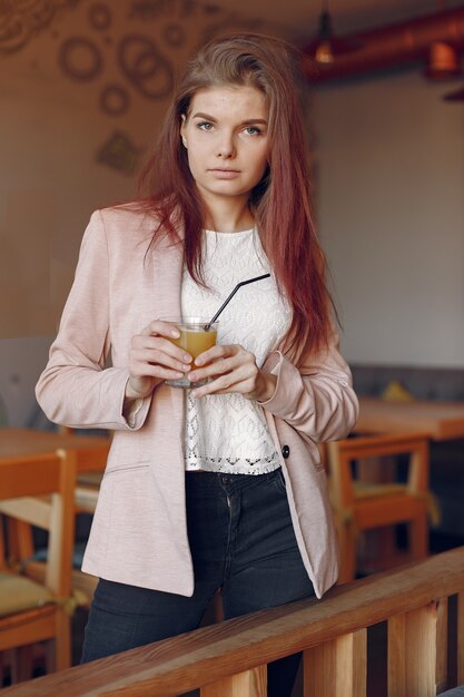 Mujer elegante en una chaqueta rosa pasar tiempo en un café