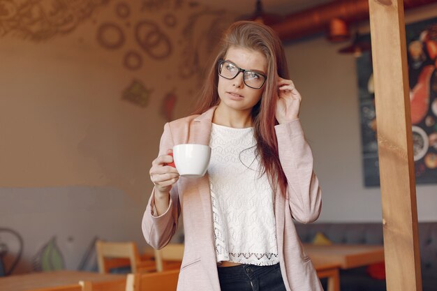 Mujer elegante en una chaqueta rosa pasar tiempo en un café