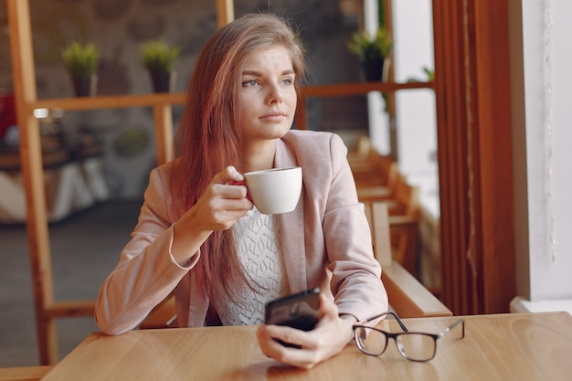 Mujer elegante en una chaqueta rosa pasar tiempo en un café