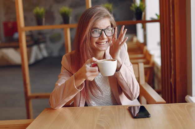 Mujer elegante en una chaqueta rosa pasar tiempo en un café