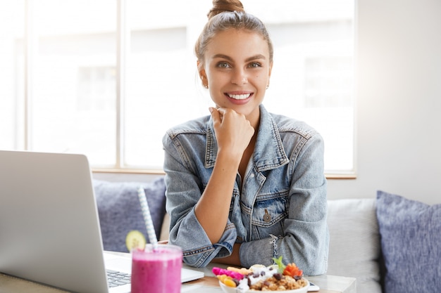 Mujer con elegante chaqueta vaquera en cafetería