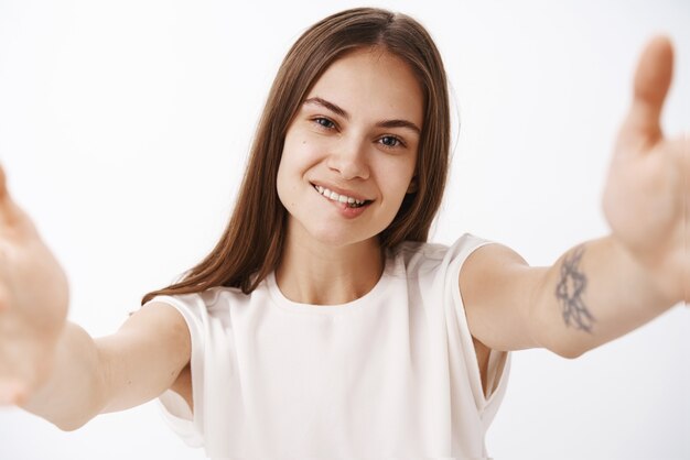 Mujer elegante despreocupada feliz segura con el pelo castaño lacio y el tatuaje que toma selfie