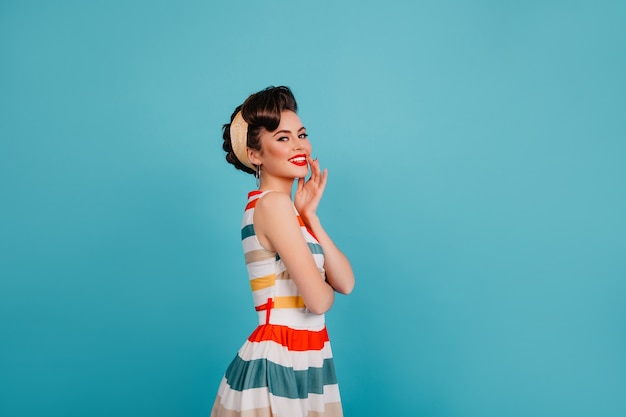 Foto gratuita mujer elegante despreocupada posando en vestido brillante. disparo de estudio de elegante chica pinup riendo sobre fondo azul.