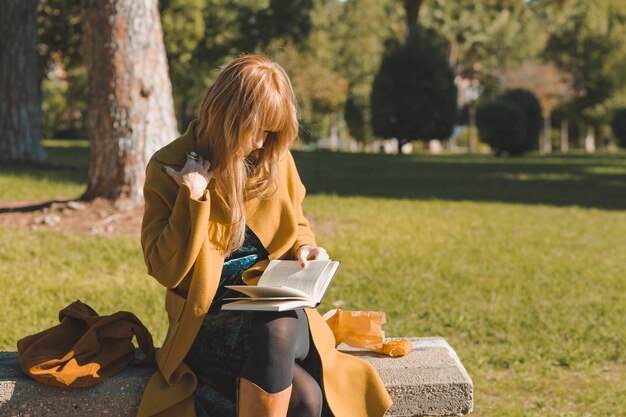 Mujer elegante disfrutando de libro en el parque