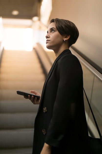 Mujer elegante en la escalera mecánica mirando a otro lado