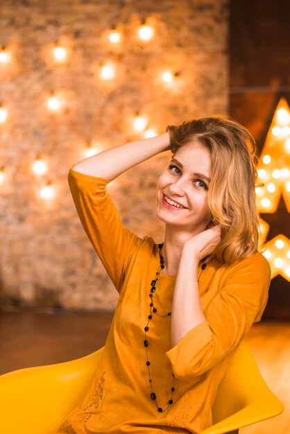 Mujer elegante y feliz en habitación con luces de navidad