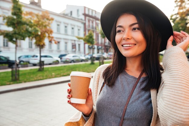 Mujer elegante feliz que sostiene la taza de café