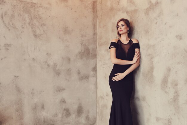 Mujer elegante y glamorosa con vestido negro posando, concepto de moda