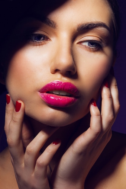 Mujer elegante glamour con labios rosados, uñas rojas y piel perfecta