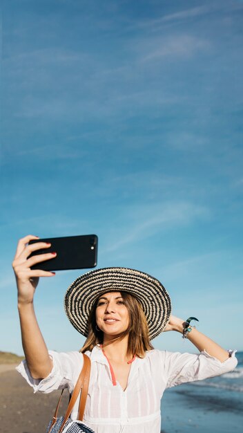 Mujer elegante haciendo selfie en la playa