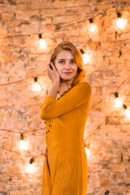 Mujer elegante joven en habitación con luces de navidad