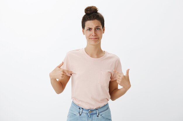 Mujer elegante joven reacia y disgustada posando contra la pared blanca