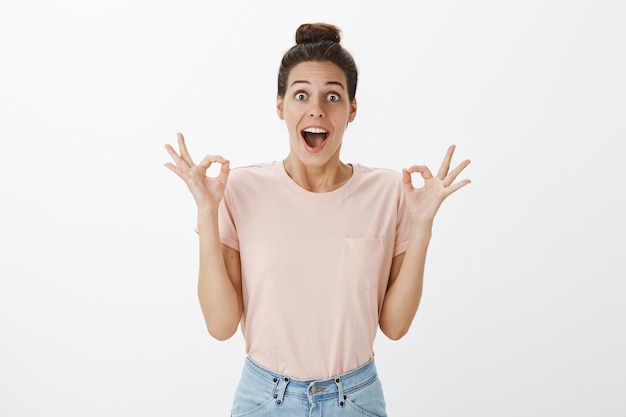 Foto gratuita mujer elegante joven satisfecha y complacida posando contra la pared blanca