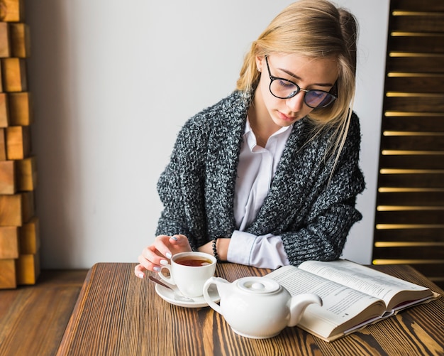 Mujer elegante con libro de lectura de té