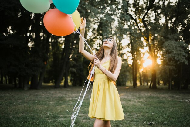 Mujer elegante en la luz del sol mirando globos