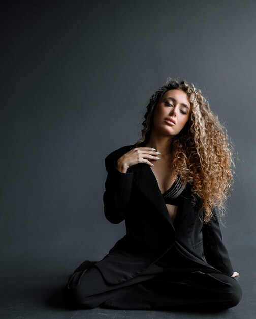 Mujer elegante con peinado afro posando con los ojos cerrados sobre fondo negro