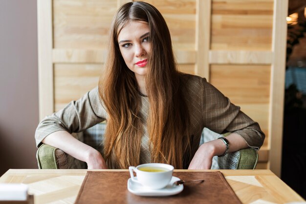 Mujer elegante con el pelo largo en una cafetería