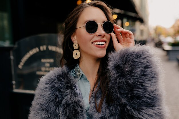 Mujer elegante con pelos oscuros posando juguetonamente en la calle.