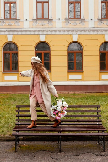 Mujer elegante con ramo de flores al aire libre en la primavera en un banco