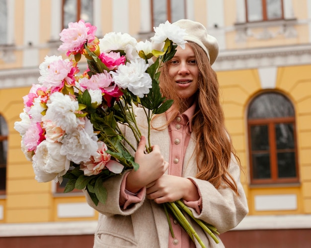 Mujer elegante con ramo de flores al aire libre en la primavera