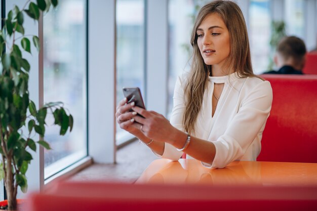 Mujer elegante en un restaurante mirando su teléfono móvil