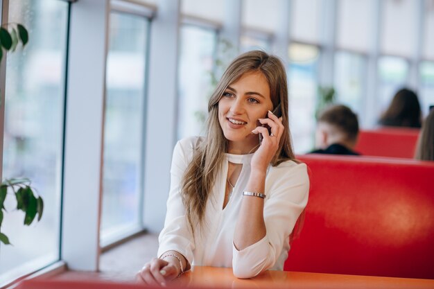 Mujer elegante en un restaurante sonriendo y hablando por un móvil