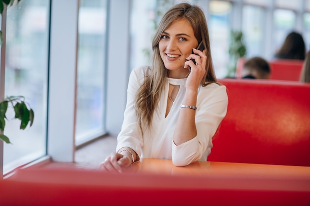 Mujer elegante en un restaurante sonriendo y hablando por un móvil