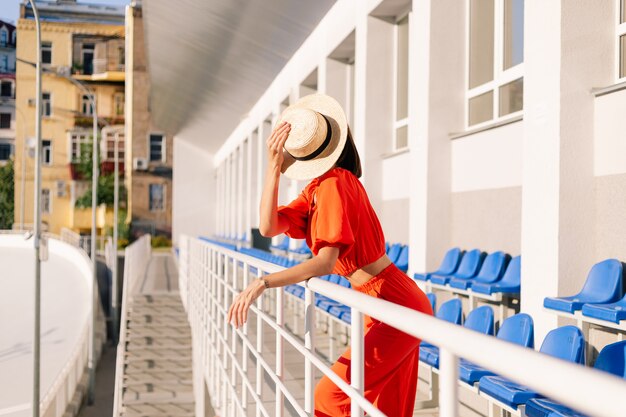 Mujer elegante en ropa naranja al atardecer en el estadio de pista para bicicletas posando