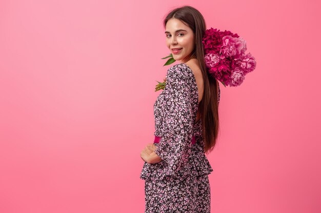 Mujer elegante en rosa en vestido de moda de verano posando con ramo de flores de peonía