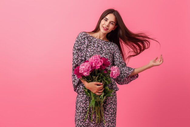 Mujer elegante en rosa en vestido de moda de verano posando con ramo de flores de peonía