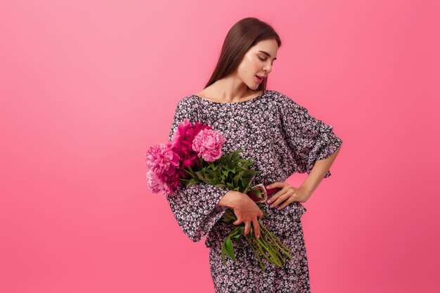 Mujer elegante en rosa en vestido de moda de verano posando con ramo de flores de peonía