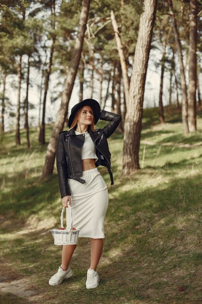 Mujer elegante con un sombrero negro en un bosque de primavera