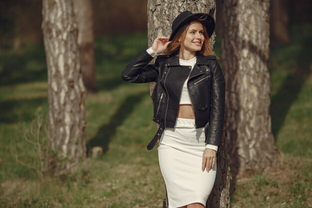 Mujer elegante con un sombrero negro en un bosque de primavera