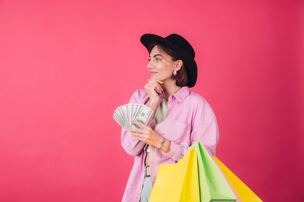 Mujer elegante con sombrero en la pared roja rosa